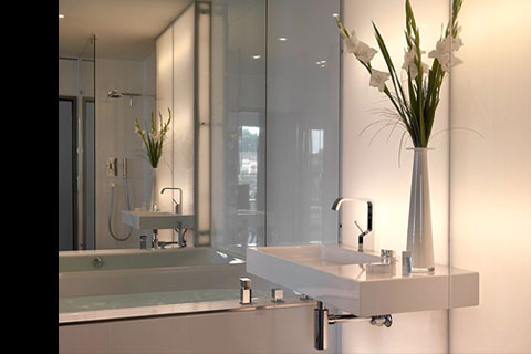 bathroom, modern washbasin, bouget of white gladiolas, large wall mirror above the bathtub