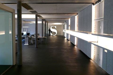 perspective of the hallway, at the end a large neon lighted logo capital S